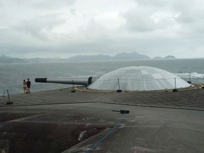 Tourists inspect the 305 mm Krupp gun battery which actively guarded the harbor until 1987 image. Click for full size.