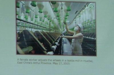 A female worker adjusts the wheels in a textile mill in Hunbaei, image. Click for full size.
