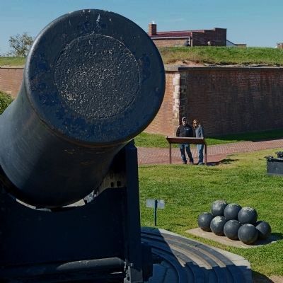 Tourists read the Outer Battery marker behind the muzzle of a 15-inch Rodman gun image. Click for full size.