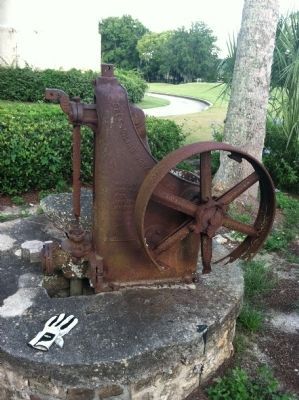 Old water pump over well at marker. Water tower in background. image. Click for full size.