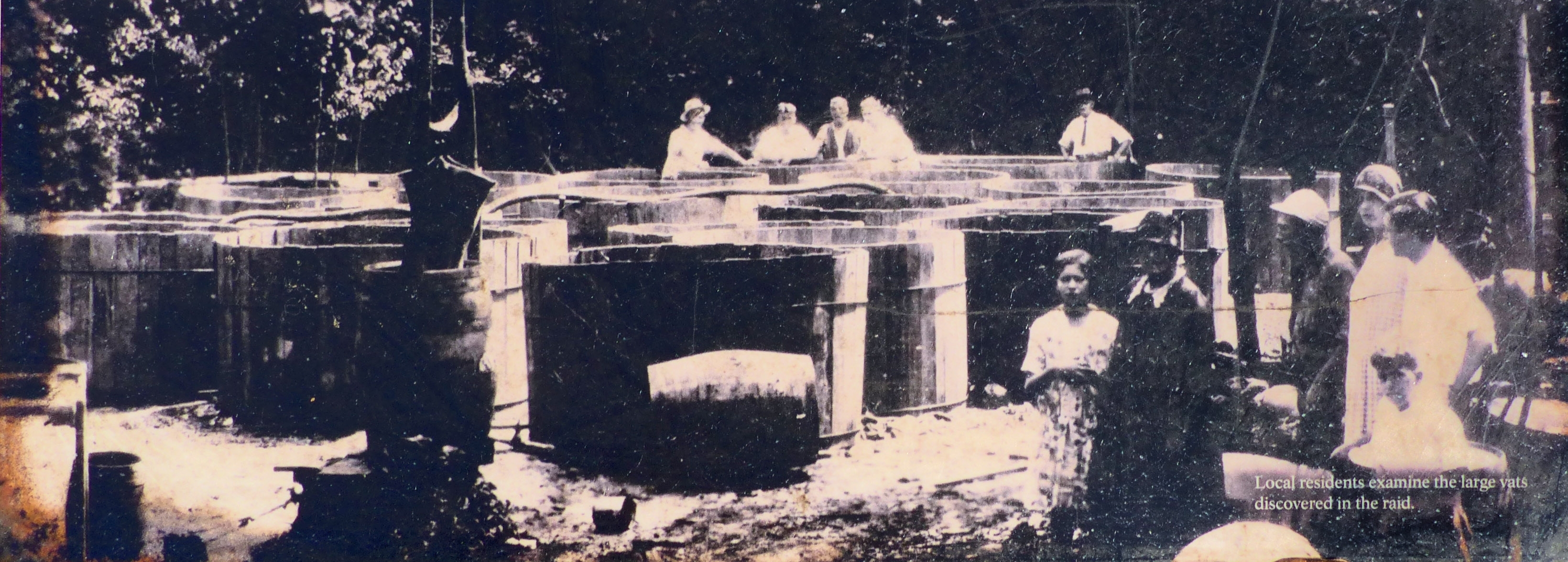 Local Residents examine the large vats discovered in the raid.