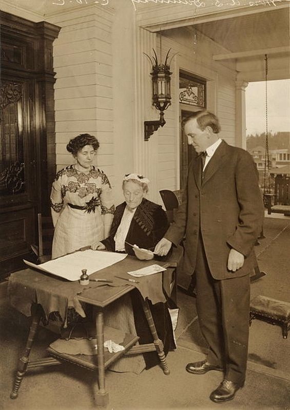 Duniway (seated) with Governor Oswald West, signing the women's suffrage amendment image. Click for full size.