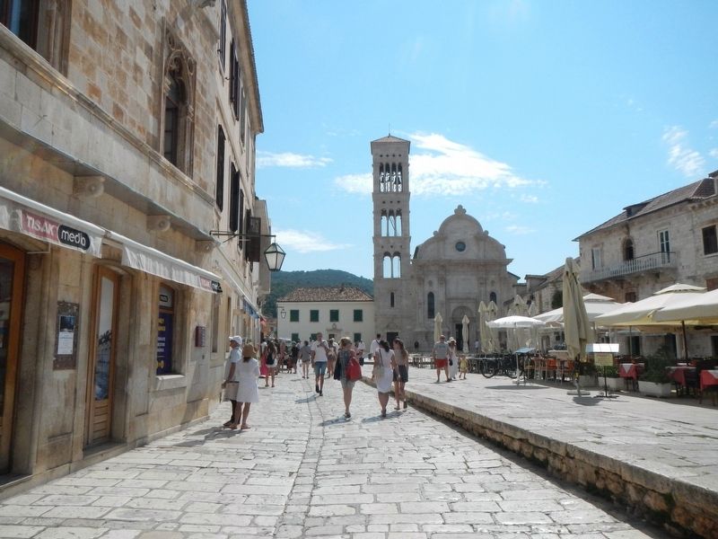 Hvar Piazza with St. Stephen's Church in the distance and the Marker on the left, image. Click for full size.