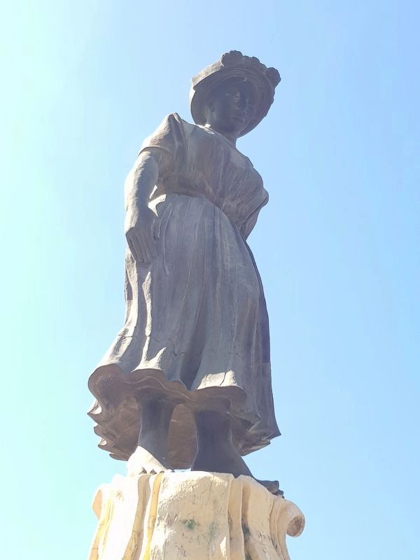 The statue depicts a Maya woman dancing along the top of the marimba image. Click for full size.