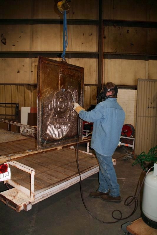 Artist Todd R. White applying patina to the Engine 1673 Marker image. Click for full size.