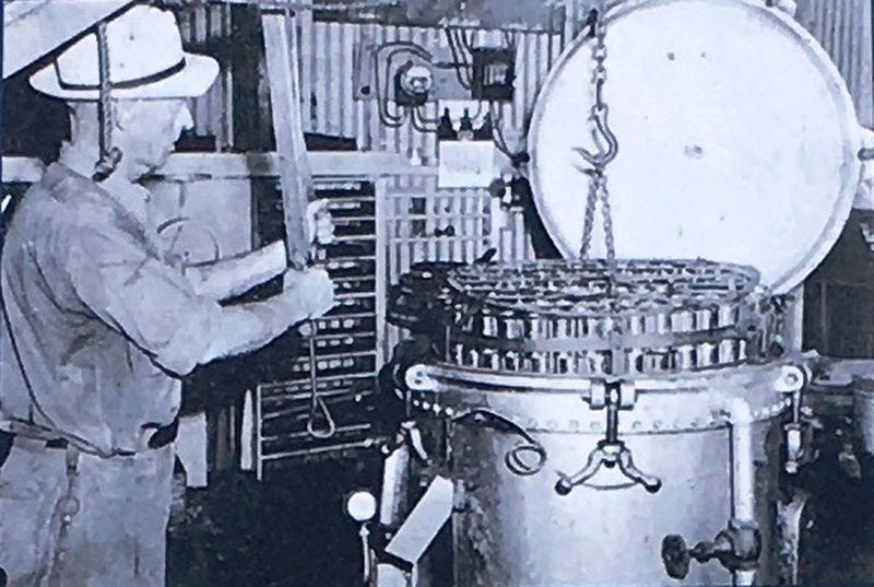 Photo Insert Center: Employee of Saint Marys Canning Company Placing cans in a pressure cooker, 1941 image. Click for full size.