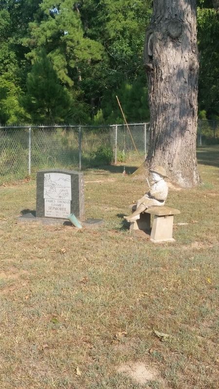 Gravestone with statue of young child fishing near the front of the cemetery gate. image. Click for full size.