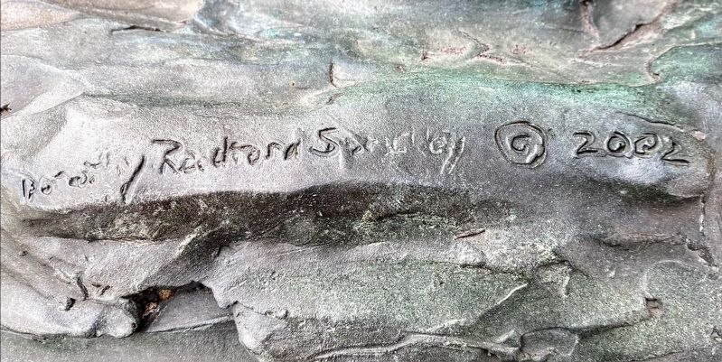 Sculptor Signature, on the side of the monument with folded hands at the base image. Click for full size.