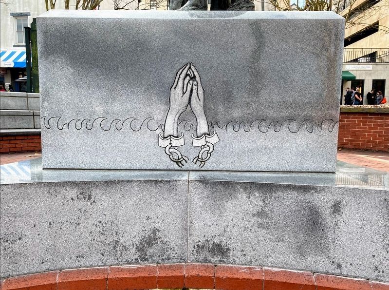 Detail on the river-facing side, showing folded hands on the monument's base image. Click for full size.