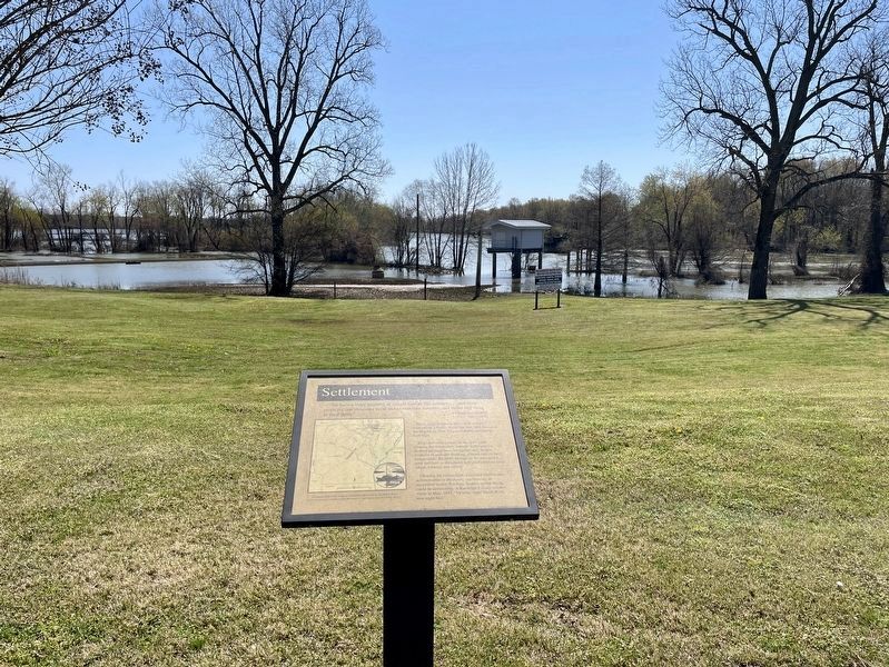 Settlement Marker with swollen Black River in background image. Click for full size.