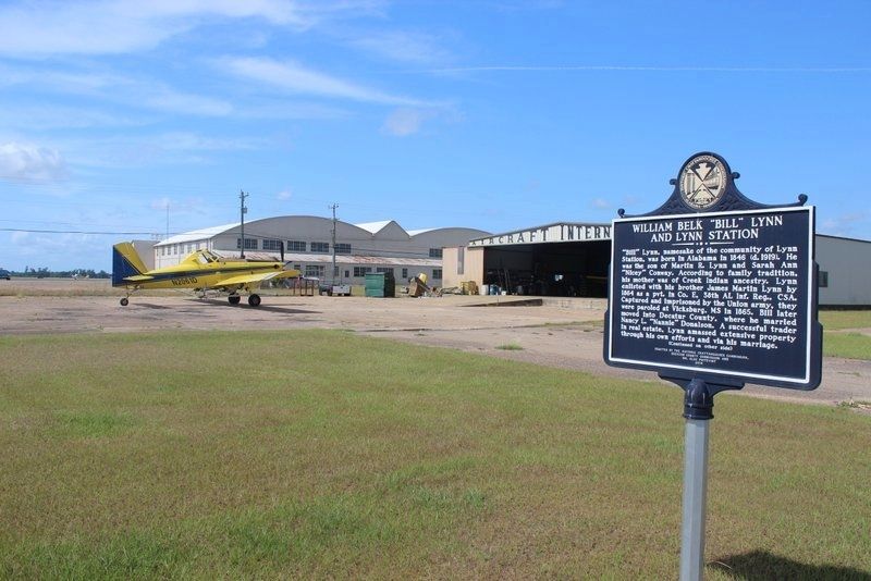 William Belk "Bill" Lynn and Lynn Station Marker looking toward WWII hanger. image. Click for full size.