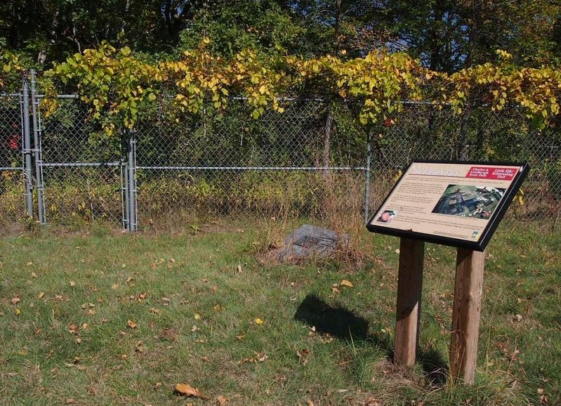Marker next to fence surrounding archaeological site image. Click for full size.