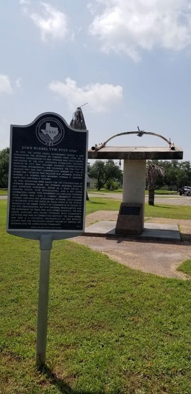 The John Wiebel VFW Post 2932 Marker in front of a war memorial image. Click for full size.