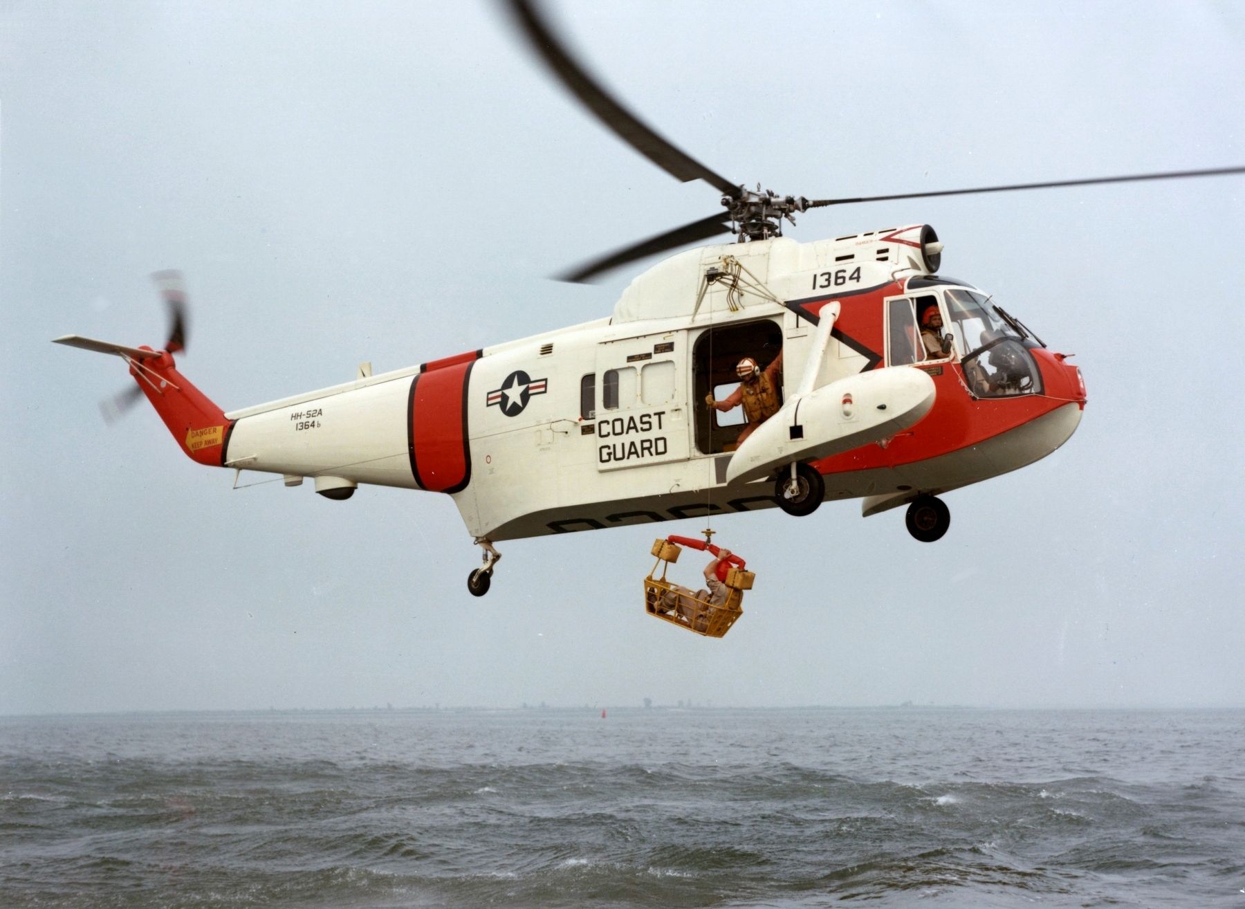 Sikorsky Helicopter HH-52A in flight with rescue basket deployed image. Click for full size.
