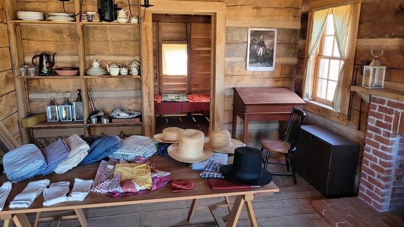 Reproduction cabin with typical household goods on the east side of the historical site image. Click for full size.
