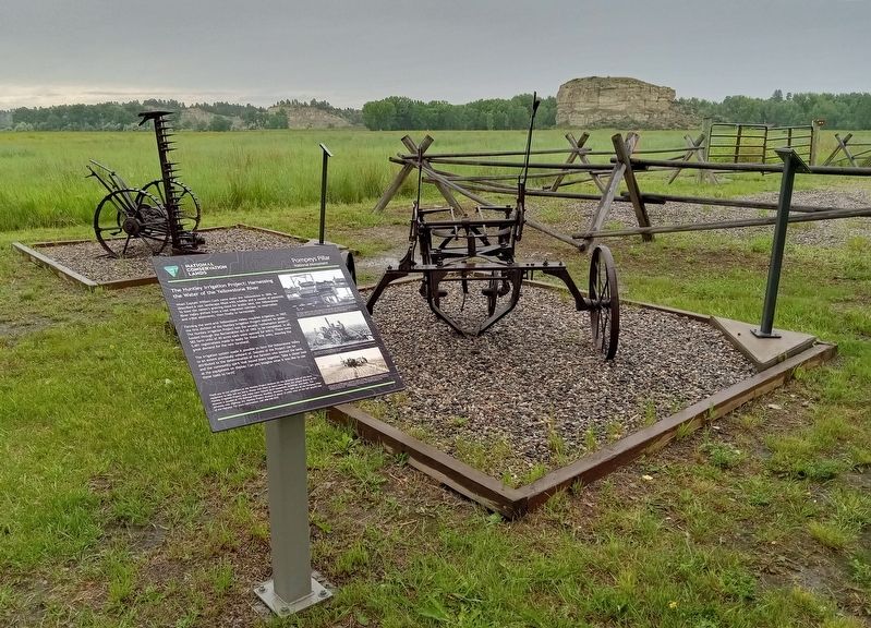 The Huntley Irrigation Project Marker and farm equipment, with Pompeys Pillar in the background image. Click for full size.