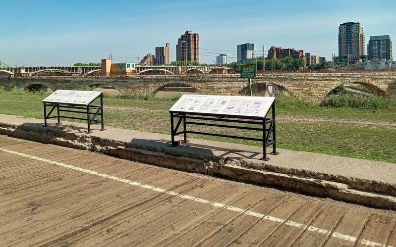 A Milling District Timeline Marker (left) overlooking the Stone Arch Bridge and Mill Ruins Park image. Click for full size.
