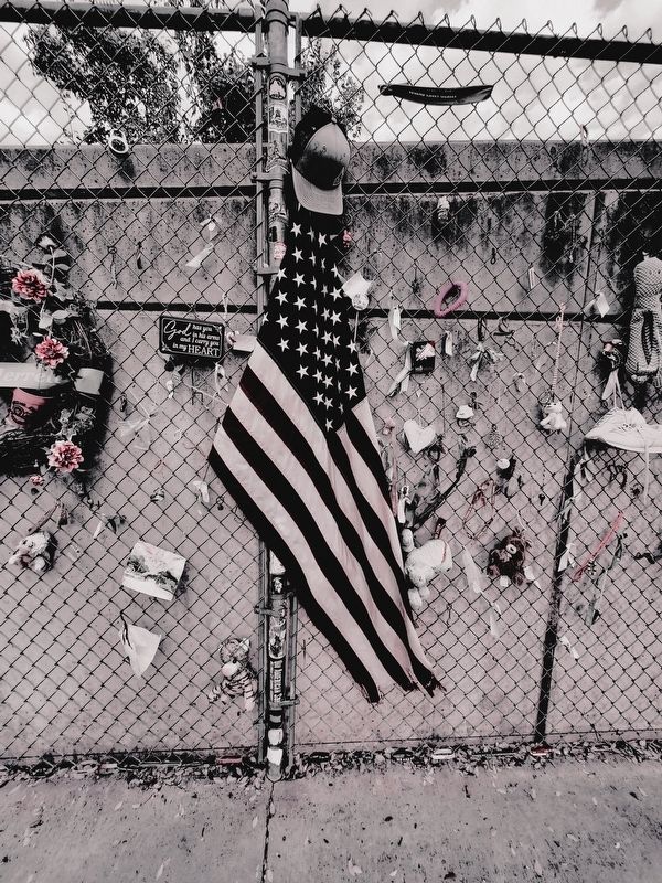 American flag and other mementos left along the fence. Click for full size. American flag and other mementos left along the fence image. Click for full size.