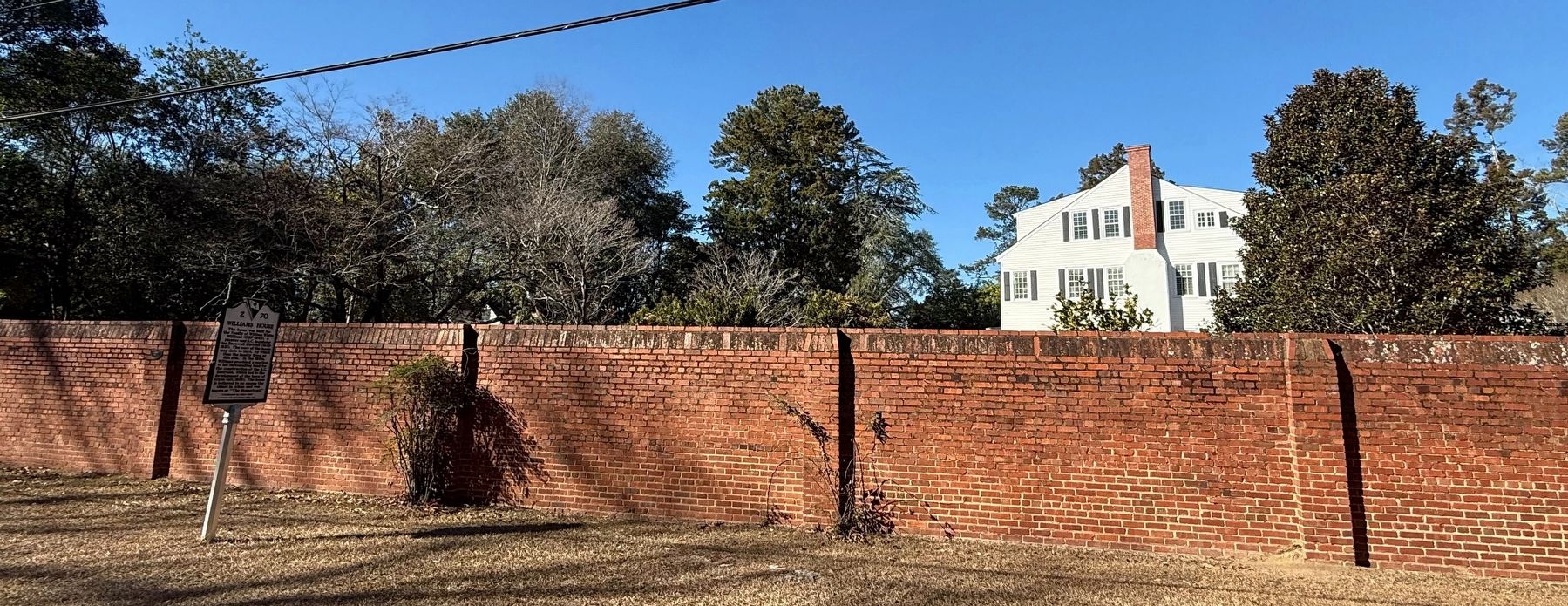 Williams House Marker with the house visible behind the brick wall image. Click for full size.