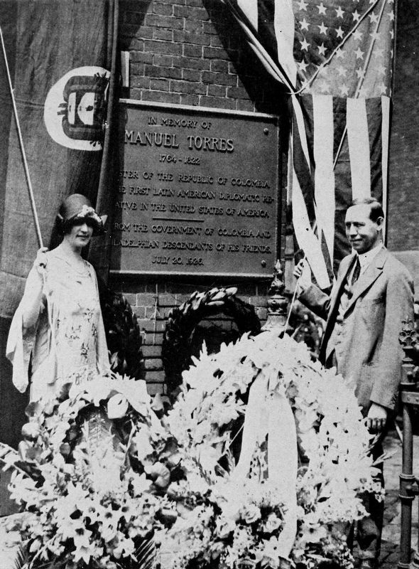 Colombian minister Enrique Olaya and his wife reveal the plaque honoring Torres. image. Click for more information.