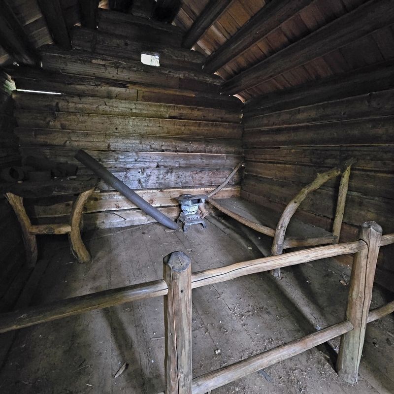 Stove, cot, and chair inside the cabin image. Click for full size.