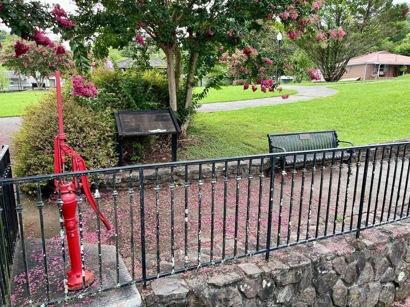marker shown to the right of spring pump with fencing surrounding spring pool in foreground image. Click for full size.