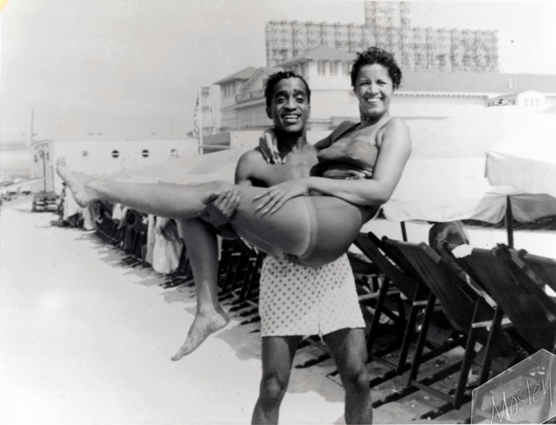 Entertainer Sammy Davis, Jr. holding a woman in his arms on Chicken Bone Beach in Atlantic City, NJ. image. Click for full size.