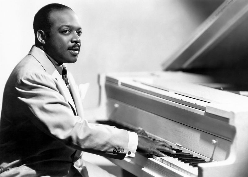 Posed photo portrait of American jazz bandleader and pianist Count Basie, seated at the piano.. Click for full size. Posed photo portrait of American jazz bandleader and pianist Count Basie, seated at the piano. image. Click for full size.
